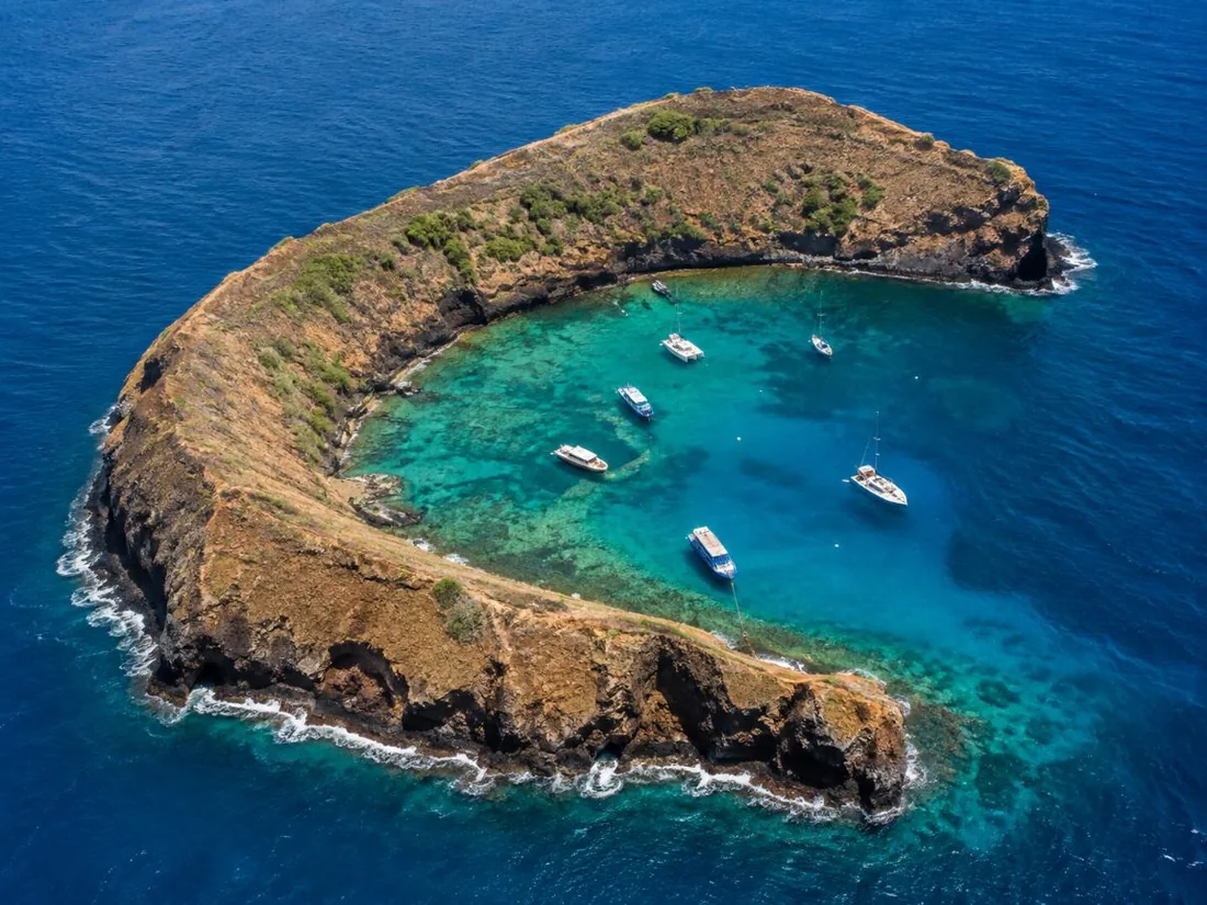 The crescent rim of Molokini seen from above, with boats moored in the sheltered inner bay